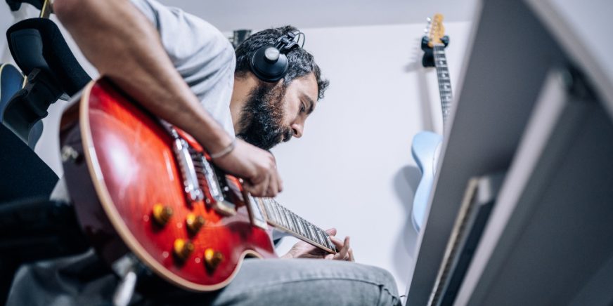 Junger Mann zuhause beim Gitarre Spielen - Powersoak oder Kopfhörer