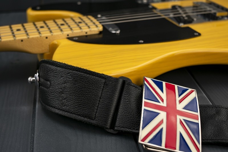 An electric guitar with a plaque emblazoned with the Union Jack on its strap