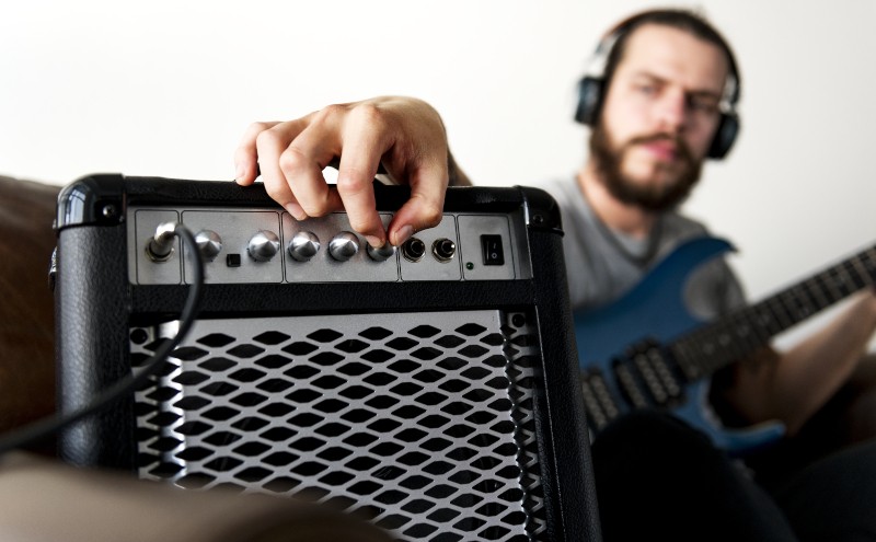 A guitarist practices with headphones in the living room at home - Best tube amps for home use