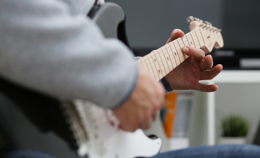 Ein Gitarrist spielt sein Instrument im heimischen Wohnzimmer Übungsamp für die Gitarre