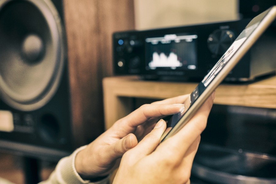 Mann nutzt Tablet, um Musik abzuspielen; im Hintergrund analoges Musiksystem