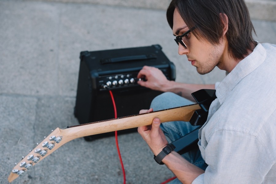 Junger Mann auf der Straße mit E-Gitarre und Min Verstärker - Mini-Röhrenverstärker