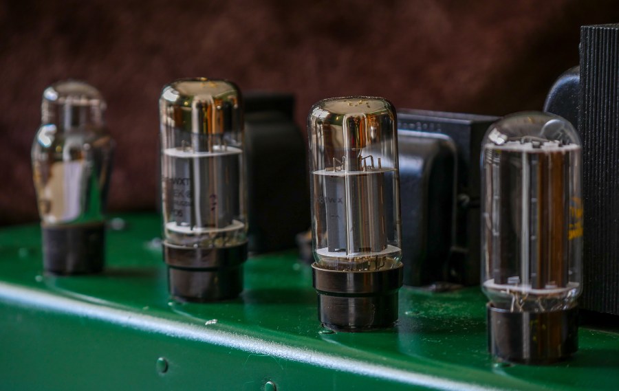 Multiple tubes are inserted side by side into the sockets of an amplifier's tube sockets