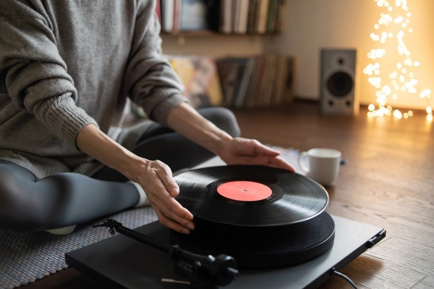 Young woman puts a record on the record player