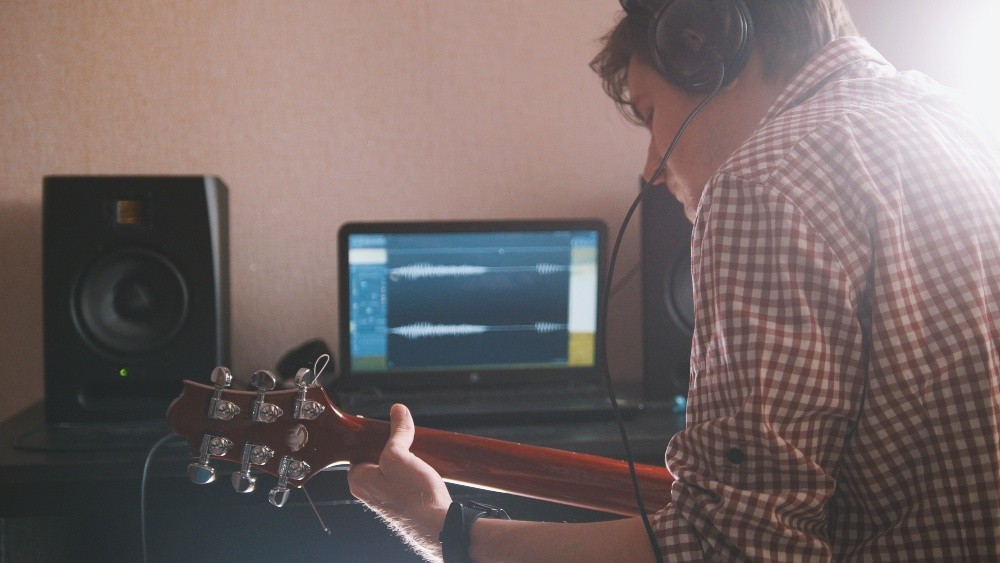 Junger Mann mit Gitarre am PC - Hybridverstärker und Modeling-Amps