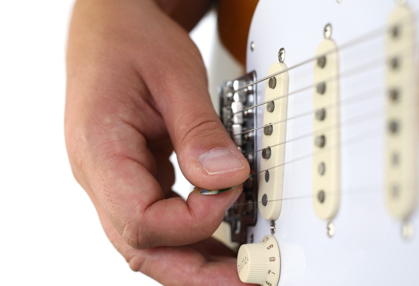 Ein Gitarrist schlägt die Saite einer E-Gitarre an