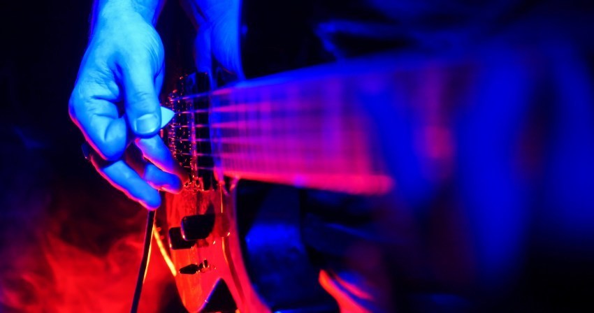 Auf einer Konzertbühne schlägt ein Rock-Gitarrist sein Instrument an Funktionsweise von Tonabnehmern